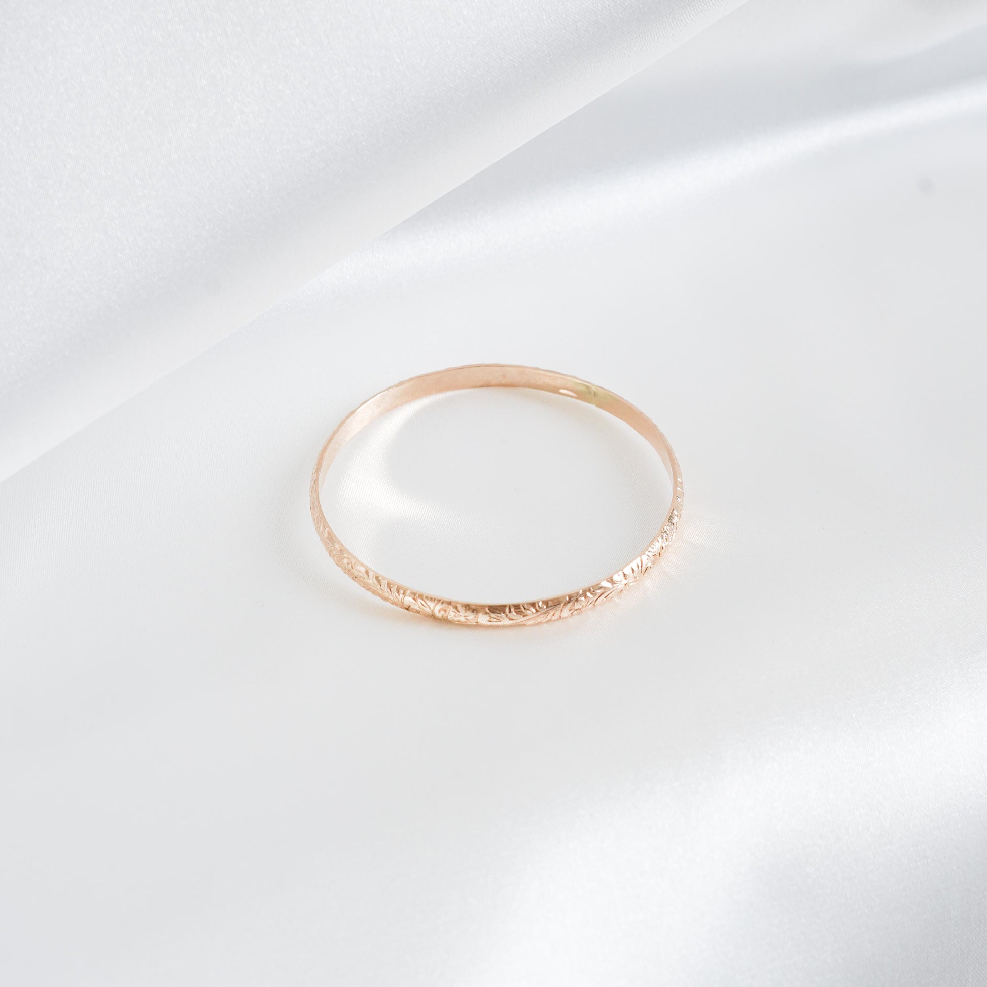 Gold heirloom bangle on white satin background
