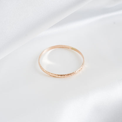 Gold heirloom bangle on white satin background