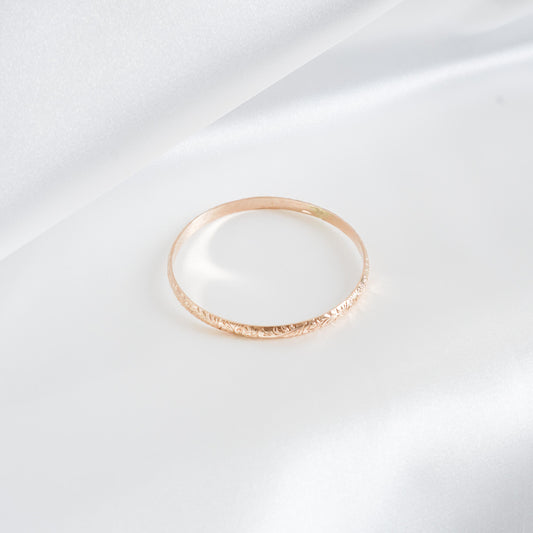 Gold bangle bracelet on white satin background