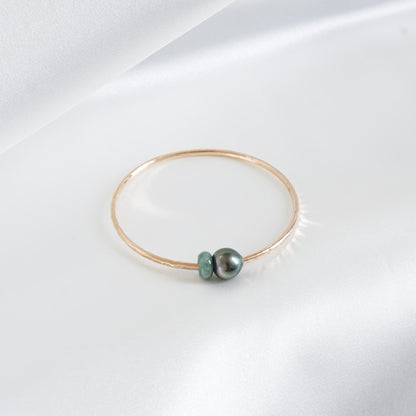 Gold bracelet with a single pearl and green jade charm on a white background