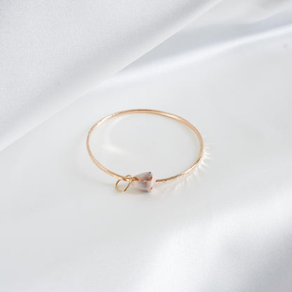 Gold bracelet with a heart-shaped charm and shell on a white background