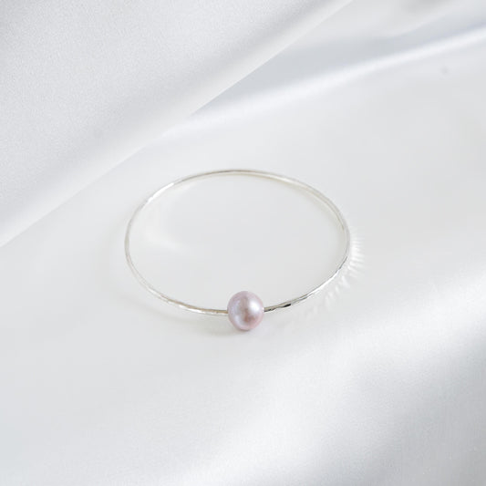 Silver bracelet with a single pearl on a white background