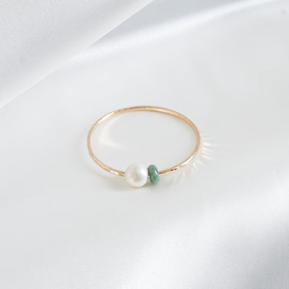 Gold bracelet with a pearl and green jade stone on a white background