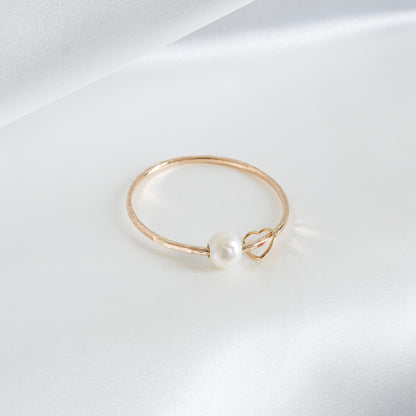 Gold bracelet with a pearl and heart charm on a white background
