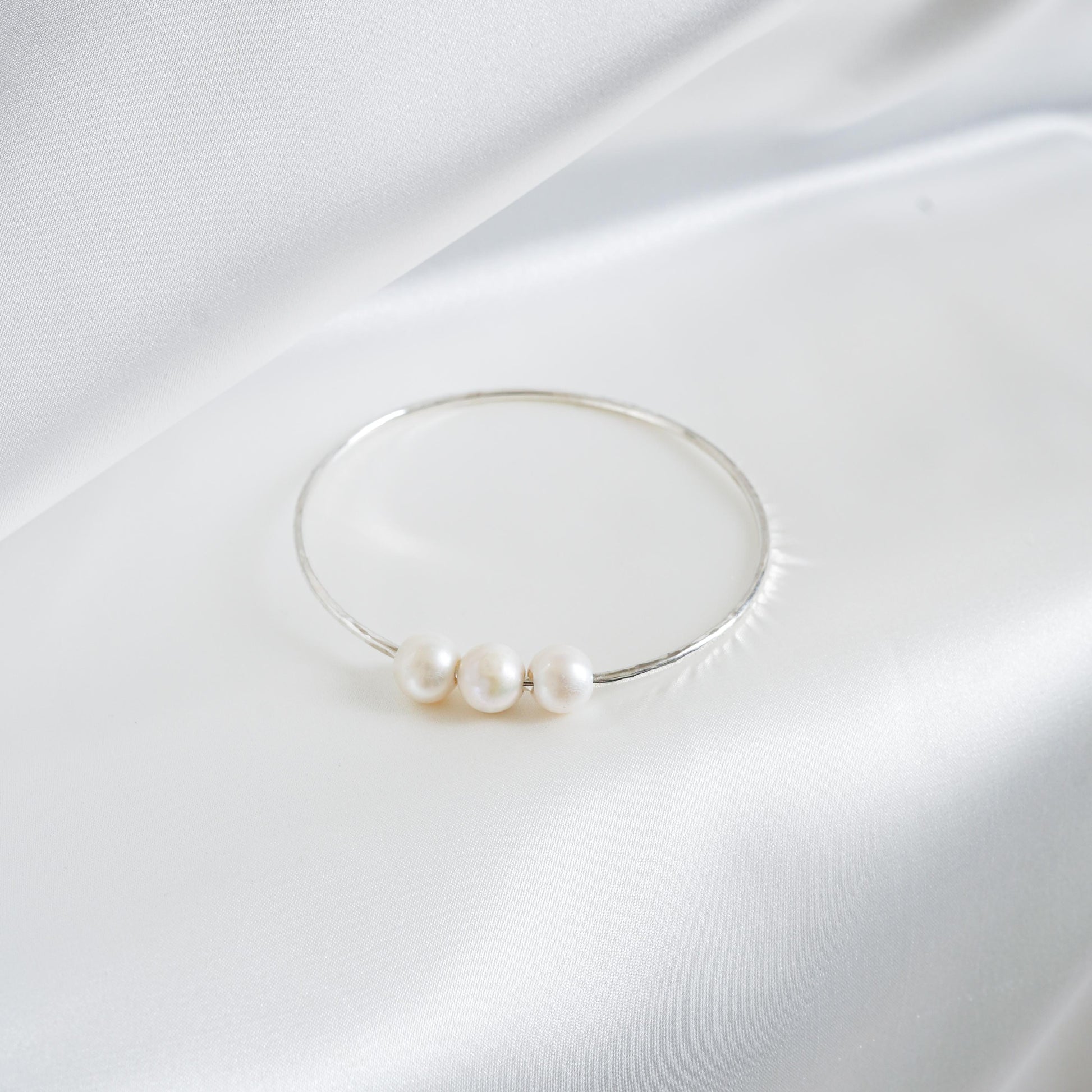 Triple pearl bracelet on a white fabric background