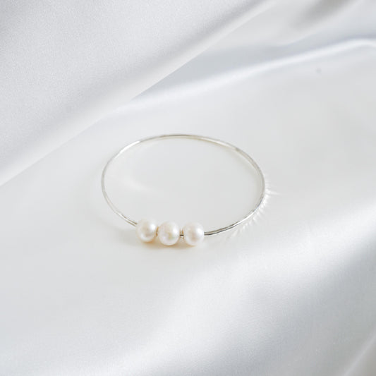 Triple pearl bracelet on a white fabric background
