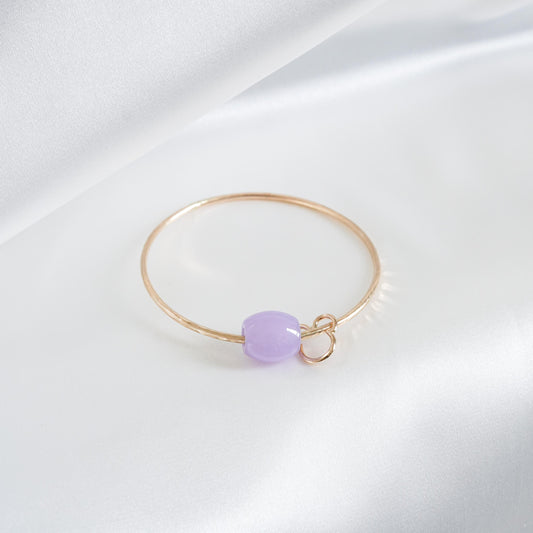 Gold bracelet with a purple jade bead and mickey mouse charm on a white background
