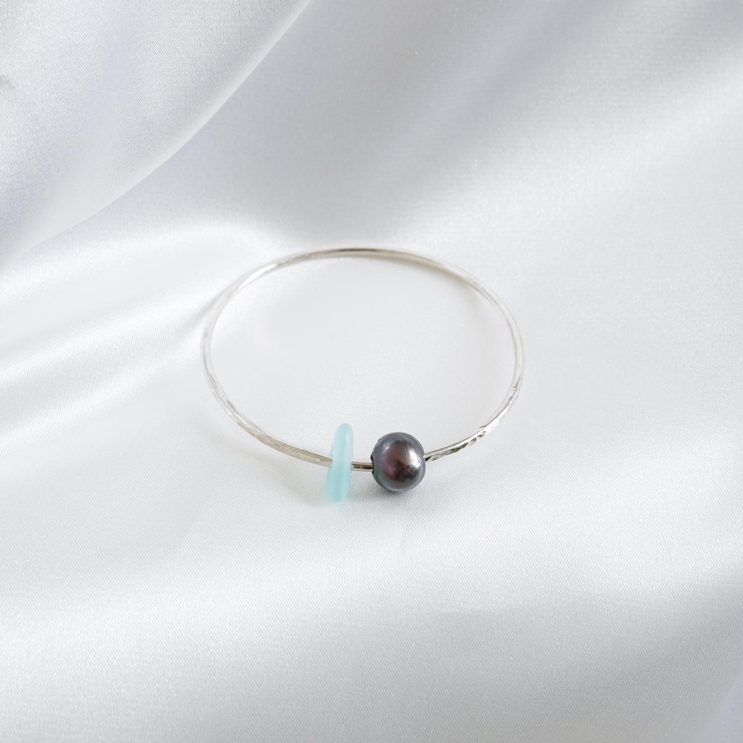 Bracelet with a tahitian pearl and blue sea glass on a white background