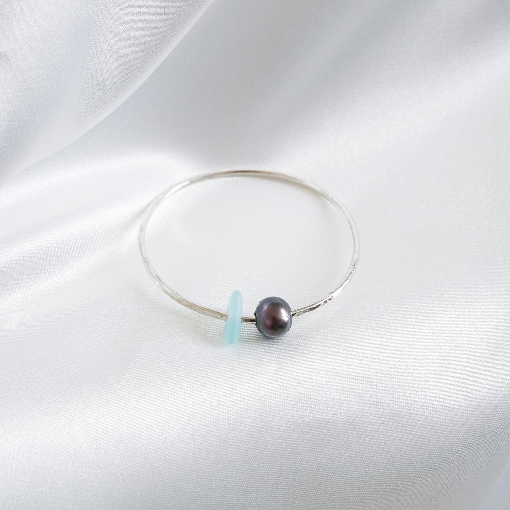 Bracelet with a tahitian pearl and blue sea glass on a white background