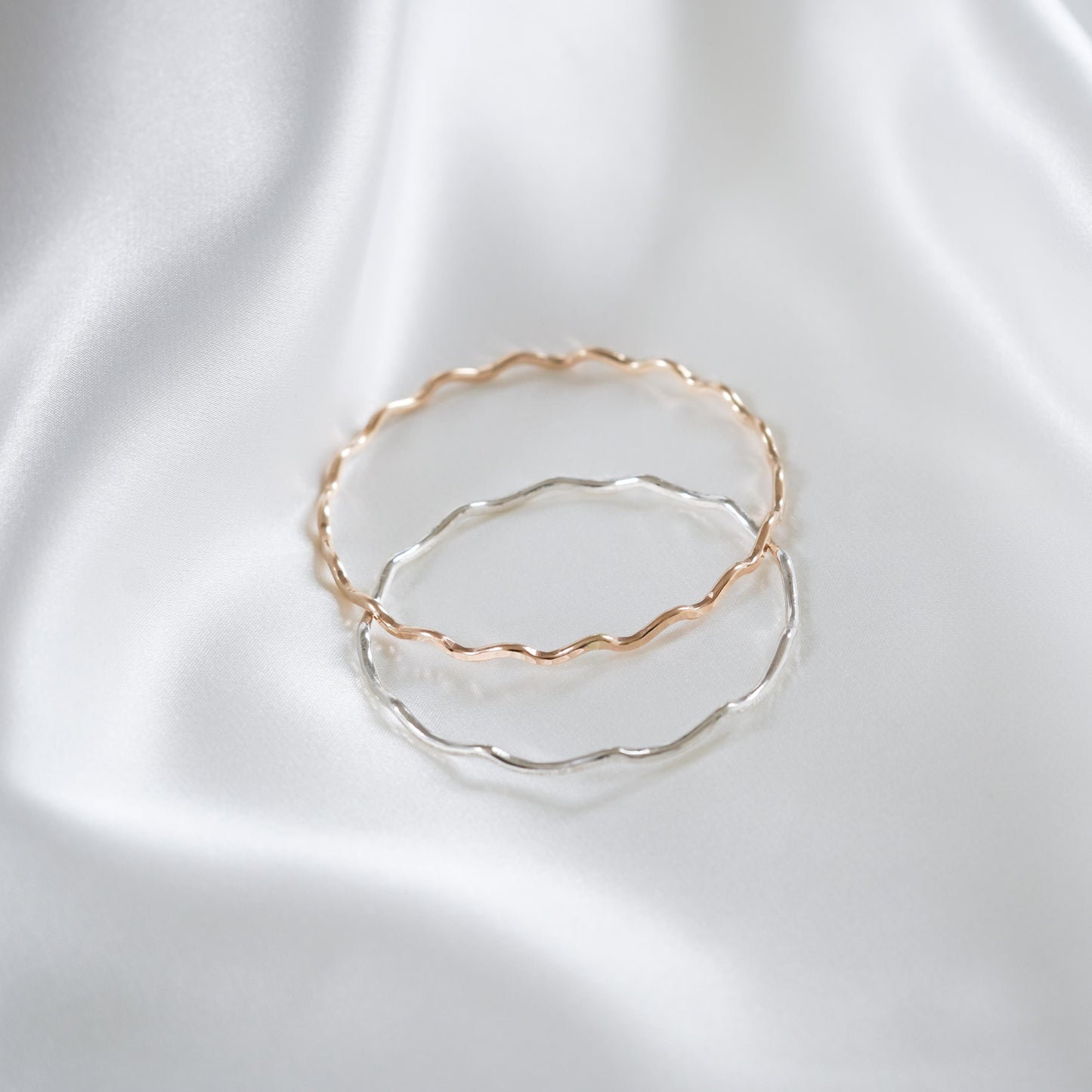Gold and silver bangles on white satin background