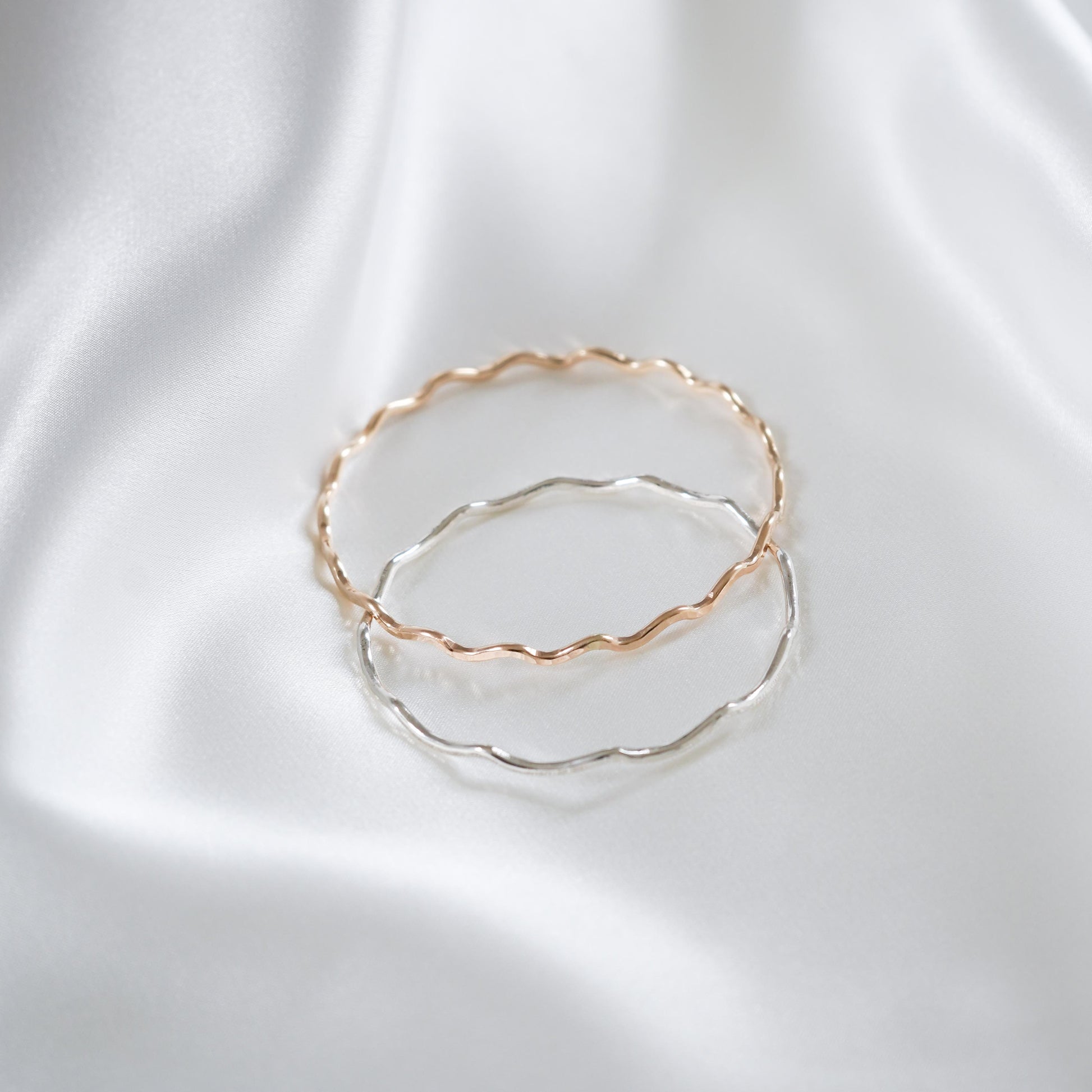 Gold and silver bangles on white satin background
