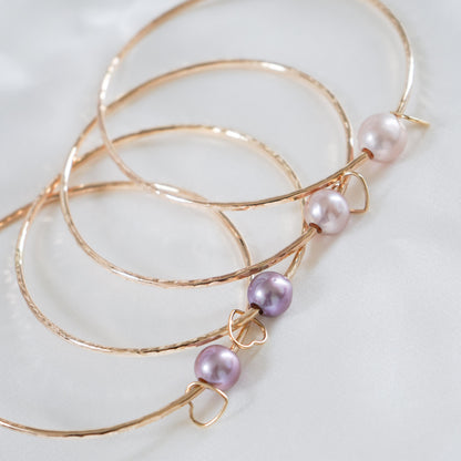 Close up of gold bangles with pink pearls 