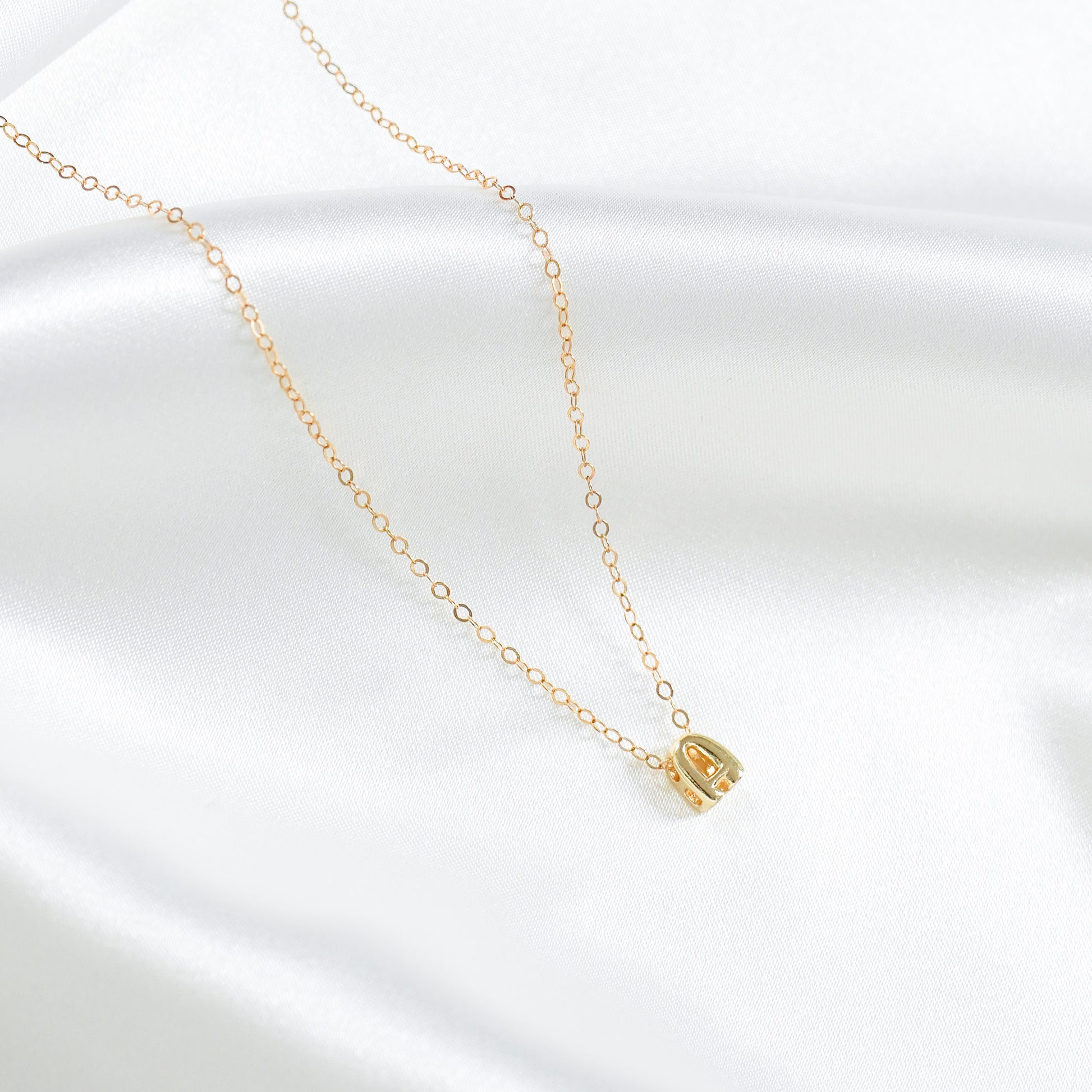 Gold necklace with a small A letter pendant on a white background