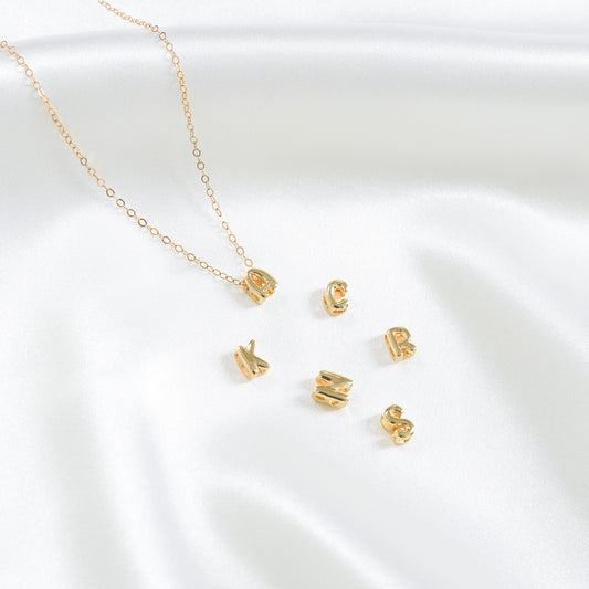 Gold necklace with A gold charm and other letter charms on a white background