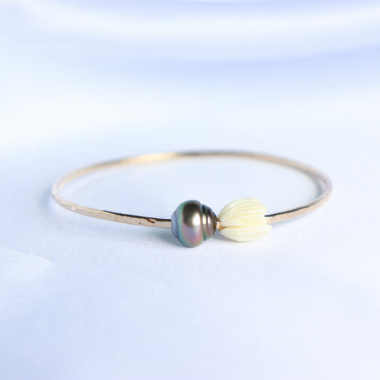 Gold bracelet with a tahitian pearl and white pikake flower bead on a white background