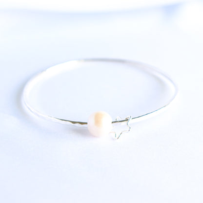 Silver bracelet with a white pearl and silver star charm on a white background
