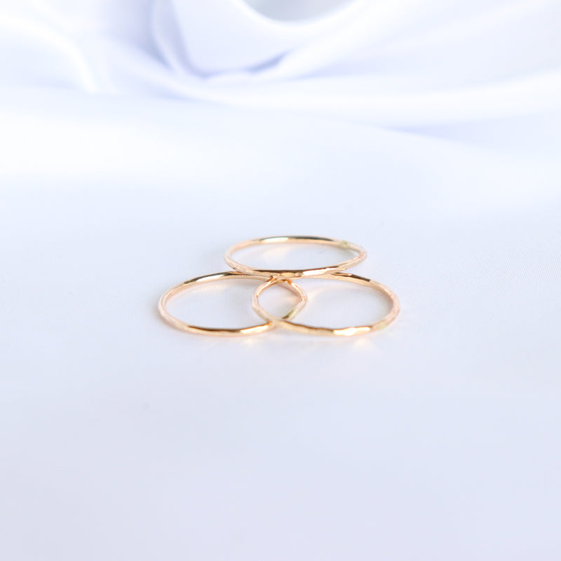Gold hammered rings on a white fabric background