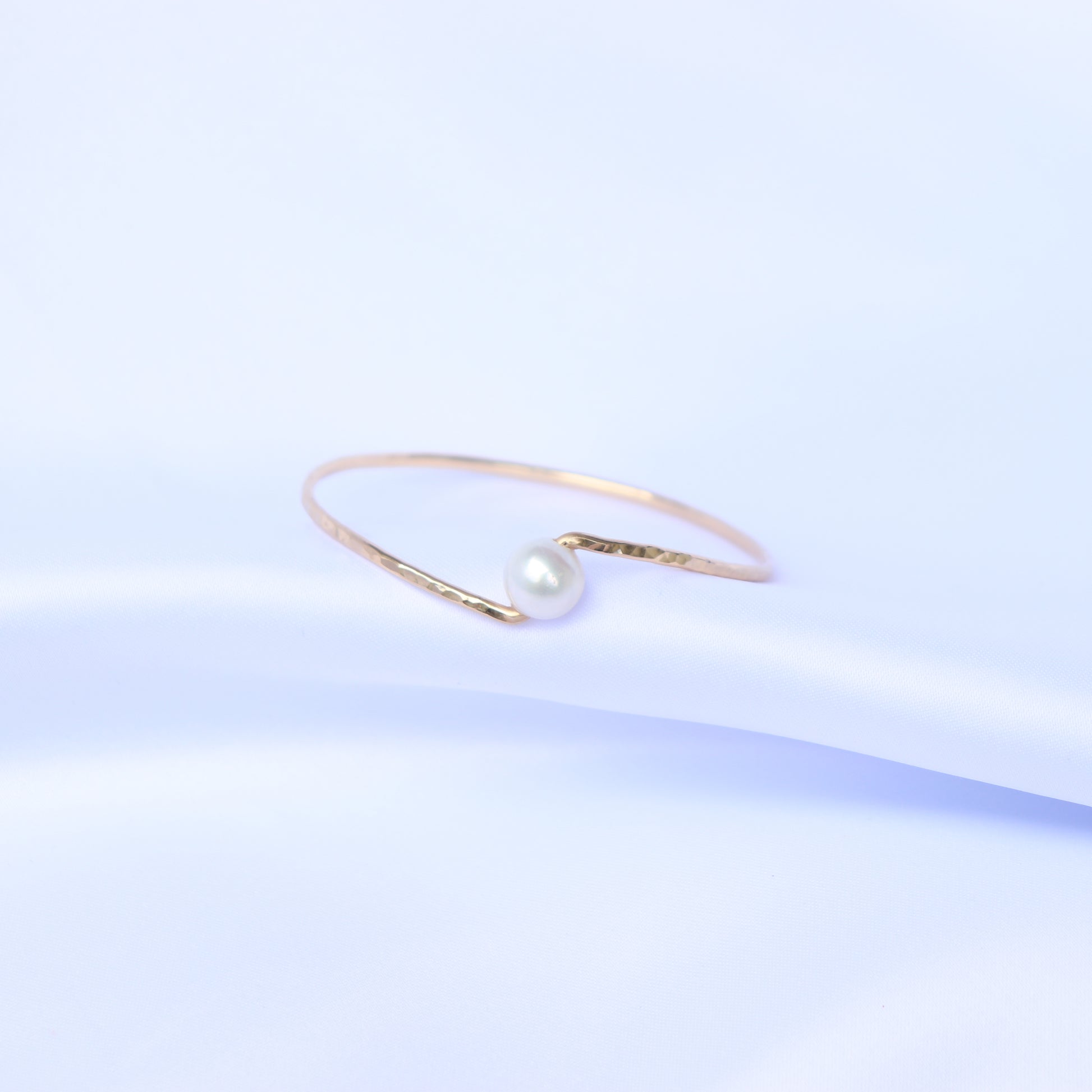 Gold bracelet with a white pearl on a white background