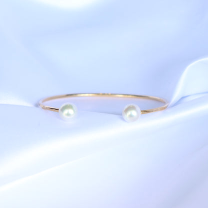 Gold bracelet with two white pearls on a white background