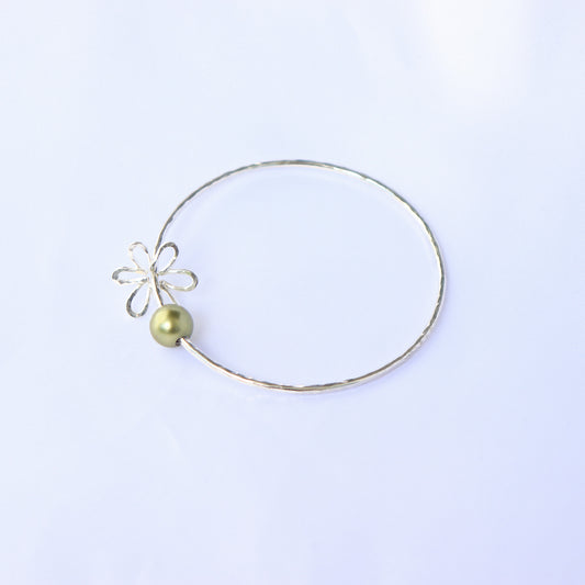 Gold bracelet with a green pearl and flower charm on a white background