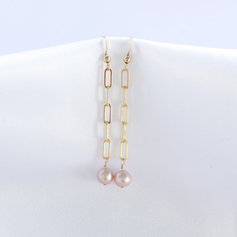 Gold chain earrings with pink pearls on a white background