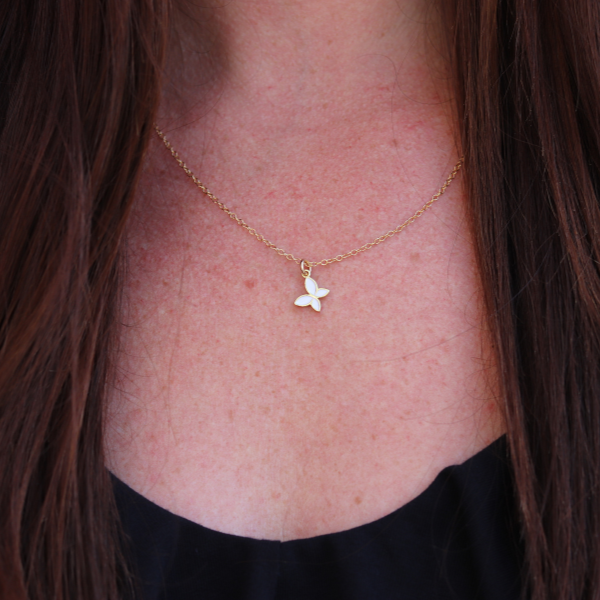 Gold necklace with a butterfly pendant on a person's neck